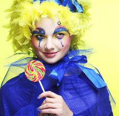 Girl with with creative make-up holds lollipop