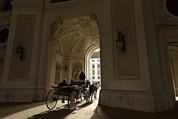 Fotobehang Traditional horse riding in a Fiaker through the gateway of Michaelertrakt in the Inner City of Vienna, Austria. © balakate