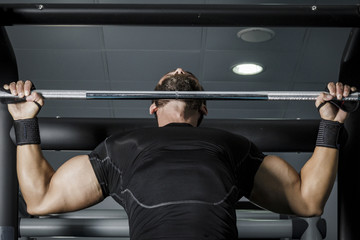 Hombre con grandes músculos levantando peso mientras entrena en el gimnasio. Ponerse en forma.