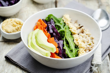 Rice bowl with red cabbage, carrots, avocado, arugula and hummus