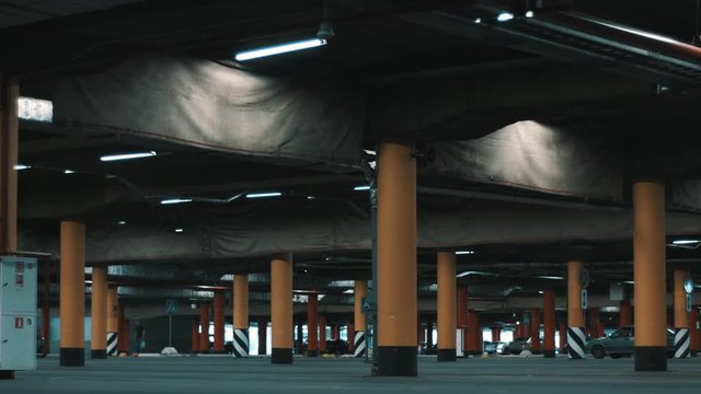 Motion shot of huge underground mall parking with cars and illumination.