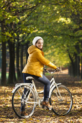 Beautiful woman riding on bike in Autumn park