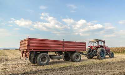 Fototapeta premium Tractor with trailer standing in a field waiting for harvest