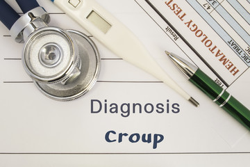 Diagnosis Croup. Stethoscope, electronic thermometer, patient blood test results lying on medical...