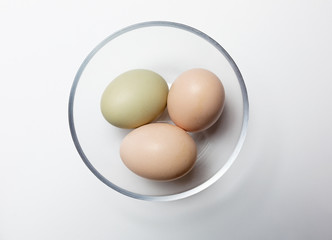 Three organic eggs in a glass bowl.