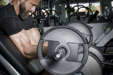 Hombre con grandes músculos levantando peso mientras entrena en el gimnasio. Ponerse en forma.
