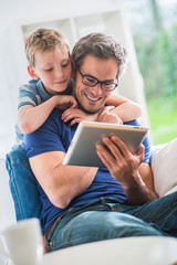 Fototapeta na wymiar At home, a father and his young son sharing a video on a tablet