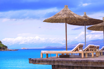Beach chairs with umbrella, wood terrace, beautiful tropical sea view