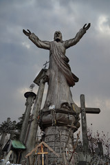Catholicism religion landmark - The Hill of Crosses in Lithuania - Statue of saint under dark cloudy sky