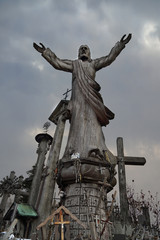 Fototapeta premium Catholicism religion landmark - The Hill of Crosses in Lithuania - Statue of saint under dark cloudy sky