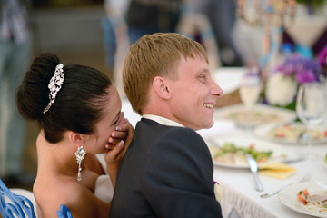 Beautiful wedding couple in restaurant. White decor for bride and groom. Colorful decoration for celebration. Beauty bridal interior for marriage. Bouquet, food and flowers in hall