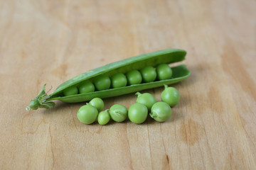 Pods of green peas on wooden cutting board close up