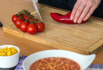 cooking process in the kitchen cherry tomatoes close-up on background female hands chopped green