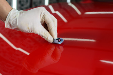 Car detailing series : Closeup of hand coating red car bonnet paint