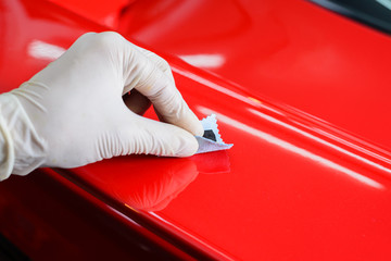 Car detailing series : Closeup of hand coating red car spoiler