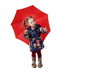 Little girl in rubber boots stands under red umbrella and shows finger isolated on white background...