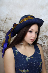 Pretty young brunette woman in blue hat portrait on abstract background