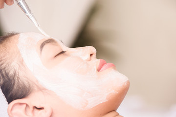 Fototapeta premium Young girl with facial mask at beauty salon 
