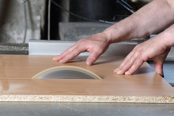 Carpenter cuts the board on rotating circular saw blade - Worker hands close up