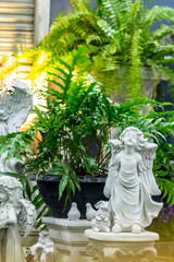 Fototapeta na wymiar Statue of Cupid in cozy garden./ Statue Cupid and waterfall in cozy garden on summer. 