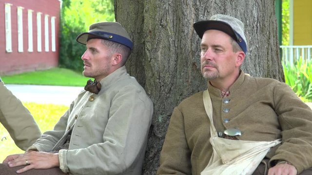 Two confederate Civil War soldiers near tree