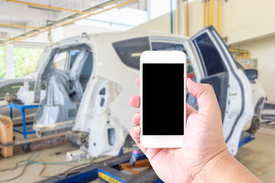 Man use mobile smartphone, blur image of auto repair service as background.