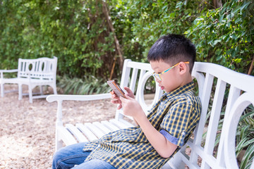 Fototapeta premium Young asian boy playing game on smart phone