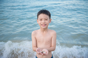 Young asian boy holding shell on the beach © gamelover