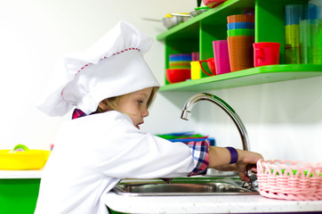 Little girl in cook hat playing in bright kitchen
