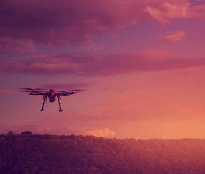 Silhouette of drone hovering in a colorful sunset. Toned image.