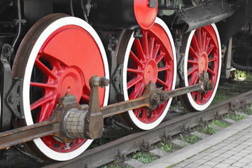 Fototapeta na wymiar Wheels of steam locomotive on rails closeup shot at an angle
