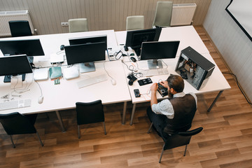 Top view on office open space with repairman. Engineer preparing workspace for work, fixing broken computer. Repair, development, business concept