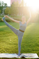 Young beautiful woman doing yoga exercises in park