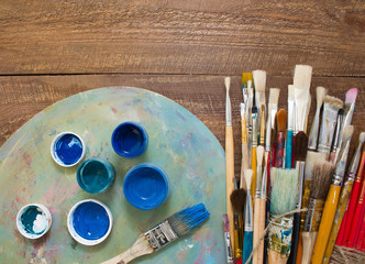 Paints, brushes and palette on the colorful background. The workplace of the artist. Banner for...