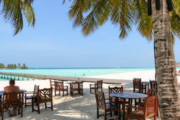 Obraz na płótnie Canvas romantic outdoor restaurant table and chairs at the beach on sun