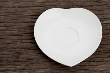 Heart-shaped ceramic dish on a wooden floor.