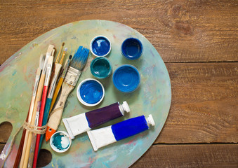 Paints, brushes and palette on the colorful background. The workplace of the artist. Banner for...