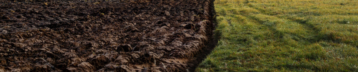 Field plowed half with soil on one side and grass on another - partition and boundary concep