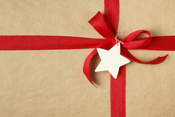 Christmas gift with bow and blank gift tag. Simple recycled wrapping paper and natural jute ribbon.