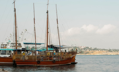 ship with lowered sails in the sea port and the views of the opposite bank