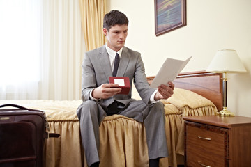 Young businessman reading document in hotel room