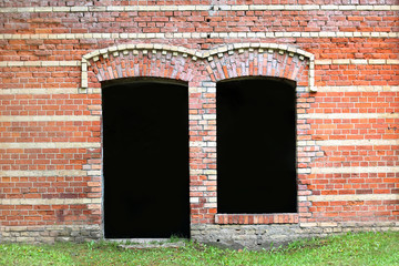 Brown brick wall with dark door and window holes