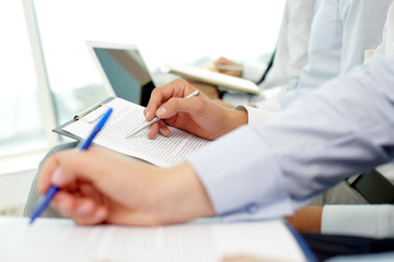 Close-up of peoples hands making written review of planned work