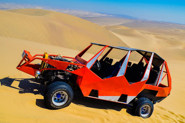 Fototapeta na wymiar Dune buggy used to carry tourists practicing sand-boarding on the dunes in Huacachina desert, Peru