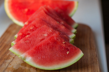 A few cloves of chopped juicy watermelon on a wooden tray.