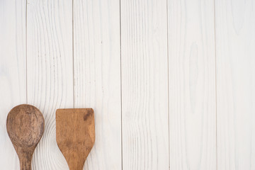 Wooden spoon and spatula on an old white table.