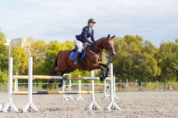 Gordijnen Young horse rider girl on equestrian competition © skumer