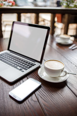 Fototapeta premium Mockup with laptop and smartphone on table in cafe