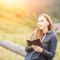 Young hiker woman sketching into notebook