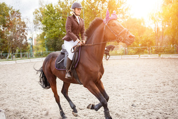 Young rider girl on horse on jumping competition